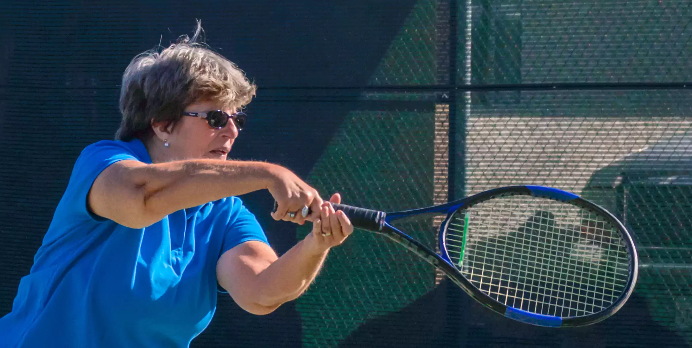 Photo: Mary hits a backhand volley. She has been playing tennis for more than 50 years.